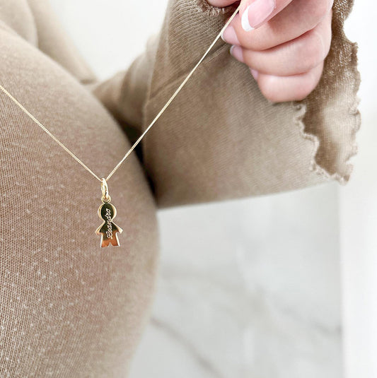 Collar formado por una cadena de color dorado con un dije de color dorado en forma de la silueta de un niño y que tiene un nombre grabado en su superficie.