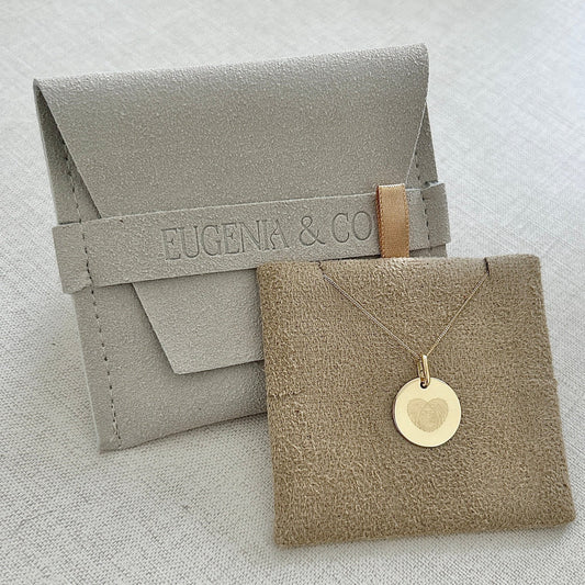 Collar formado por una cadena de color dorado con un dije de color dorado que tiene un corazon formado por dos huellas digitales grabado en su superficie.