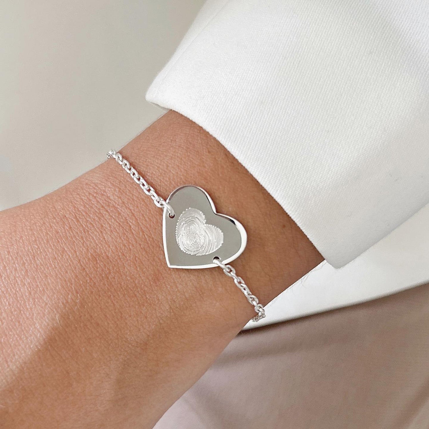 Pulsera formada por una cadena de color plateado con un dije de color plateado con forma de corazón. 