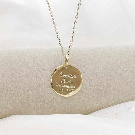 Collar formado por una cadena de color dorado con un dije de color dorado que tiene una frase grabada en su superficie.